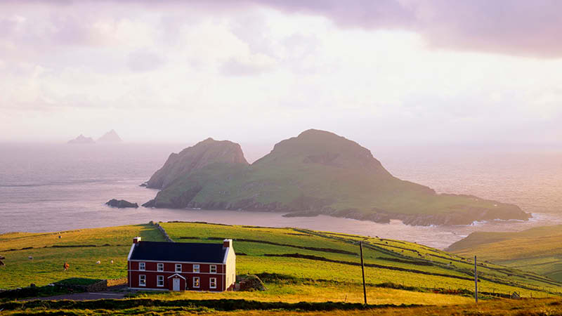 Det natursköna Ring of Kerry med hus, åker och berg i havet, rundresa på Irland.